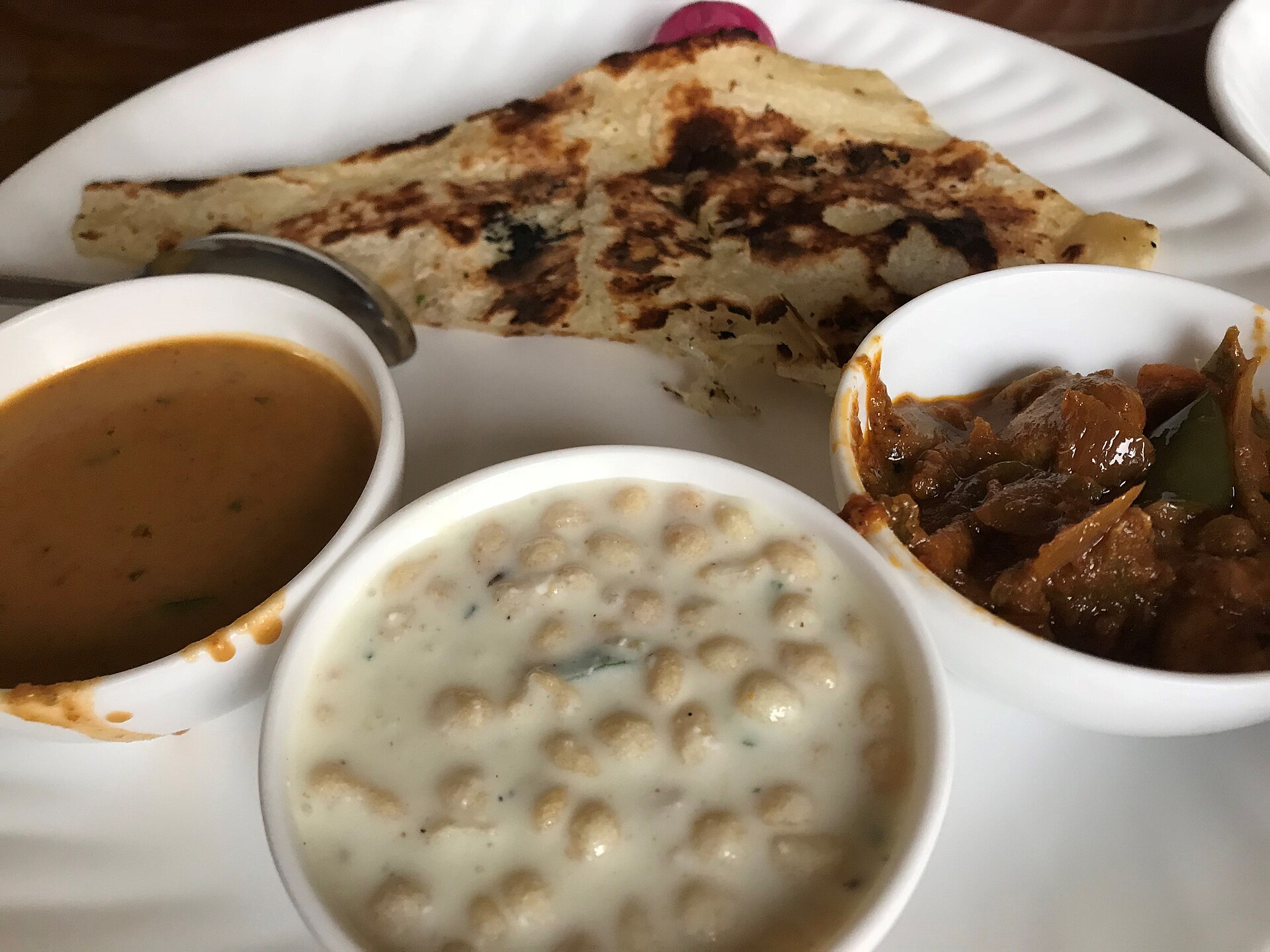 A vegetarian meal of paratha, dal, raita and kofta curry